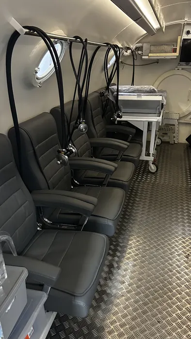 Interior da câmara hiperbárica com poltronas reclináveis e máscaras de oxigênio
