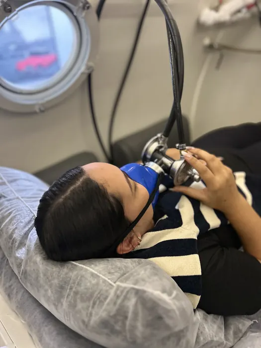 Paciente deitada durante sessão de oxigenoterapia hiperbárica, acompanhada de perto
