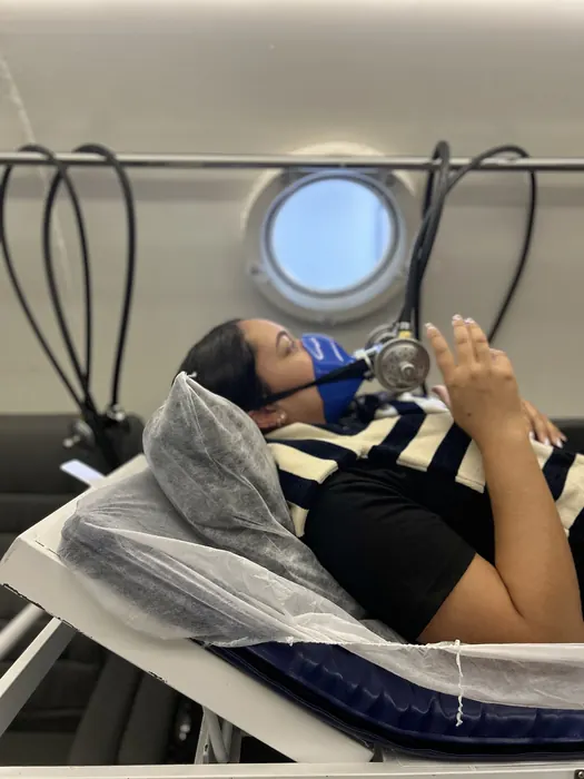 Paciente tranquila durante sessão na câmara hiperbárica, próxima à vigia de observação